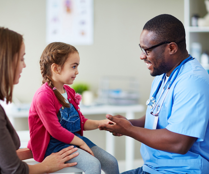 un doctor examinado a una niña con su madre al lado